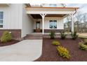 Inviting front porch with brick accents, wood ceiling, and landscaped garden at 8624 Dukes Lake Rd, Zebulon, NC 27597