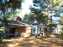 Beautiful brick home with a carport and inviting entrance with white pillars, nestled under mature trees for added curb appeal at 6349 Elevation Rd, Benson, NC 27504