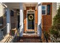 Inviting brick entryway with black door adorned with a wreath, black railings, and hanging lanterns at 229 Rose Walk Ln, Carrboro, NC 27510