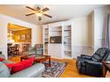 Living room featuring hardwood floors, ceiling fan, built-in shelving, and comfortable seating at 229 Rose Walk Ln, Carrboro, NC 27510