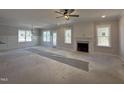 Open-concept living room with a modern ceiling fan and large windows with backyard views at 103 Roma Gora Ct, Princeton, NC 27569