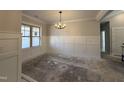Formal dining area features elegant wainscoting and stylish chandelier lighting at 702 Tuscany Cir, Princeton, NC 27569