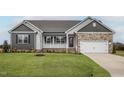 Charming single-story home featuring stone accents, covered porch, lush lawn, and an attached two-car garage at 11340 International Dr, Middlesex, NC 27557
