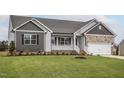 Charming single-story home with stone accents, covered porch, manicured lawn, and attached garage at 11340 International Dr, Middlesex, NC 27557
