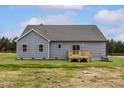 View of the back of a house with gray siding and a small, wooden deck and grassy yard at 11376 International Dr, Middlesex, NC 27557