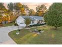 Home featuring a two-car garage, manicured lawn, mature landscaping, and a decorative pond at 185 Franklin Ln, Henderson, NC 27537