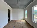 Well-lit room with a decorative tray ceiling and large windows offering natural light at 6044 Scalybark Road, Durham, NC 27712