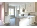 Bright kitchen featuring white cabinets, a marble countertop island, and stylish backsplash at 180 Brunswick Dr, Nashville, NC 27856