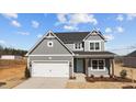 Charming two-story home featuring gray siding, a two-car garage, and a welcoming teal front door at 585 Husketh Rd, Youngsville, NC 27596