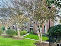 Brick townhome row with mature crepe myrtle trees and landscaped lawn along the sidewalk, creating an inviting neighborhood scene at 710 N Person St # 304, Raleigh, NC 27604