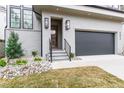 Modern home entrance with gray brick, dark trim, landscaping, and a black garage door at 2417 Mayview Rd, Raleigh, NC 27607