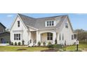 Beautiful white brick home with a covered porch, black railings, manicured lawn, and a pond view at 3804 Cobbler View Way, Fuquay Varina, NC 27526
