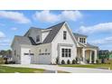 Elegant white home with a three-car garage, manicured landscaping, and charming covered porch at 3804 Cobbler View Way, Fuquay Varina, NC 27526