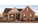 Charming brick home featuring a covered porch, multiple windows, and manicured landscaping at 7553 Sweetwater Dr, Nashville, NC 27856