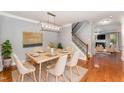 Well-lit dining room with stylish light fixture, hardwood floors, and access to the staircase at 552 Stobhill Ln, Holly Springs, NC 27540