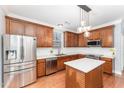 Modern kitchen with stainless steel appliances, wood cabinetry, and a center island at 552 Stobhill Ln, Holly Springs, NC 27540