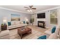 Bright living room with a cozy fireplace, neutral color palette, and a ceiling fan at 552 Stobhill Ln, Holly Springs, NC 27540