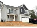 Two-story home with gray siding, black shutters, covered porch, and attached garage at 60 Bennett Rd, Coats, NC 27521