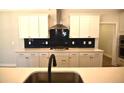 Stylish kitchen showcasing white cabinets, a striking dark backsplash, and a central island with modern fixtures at 35 Accord Dr, Youngsville, NC 27596
