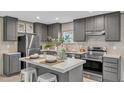 Modern kitchen features stainless steel appliances, gray cabinets, a kitchen island, and natural light from the window at 1235 Schloss Rd, Louisburg, NC 27549