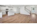Open-concept living space with wood floors that connects the kitchen and stairway at 909 Montague Ave, Durham, NC 27703
