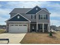 Two-story home featuring a gray exterior, stone accents, and a two-car garage on a landscaped lot at 105 Wilderness Ct, Mebane, NC 27302