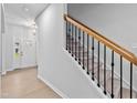 Bright hallway with light-colored wood floors and a staircase featuring a wooden handrail and black metal balusters at 2750 Lacy Holt Rd, Graham, NC 27253