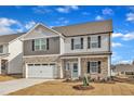 Charming two-story home featuring stone accents, neutral siding, an attached two-car garage, and a bright blue front door at 517 Southwick Pl, Mebane, NC 27302