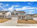 A traditionally styled home with a two car garage, a gray and stone facade, and professionally landscaped lawn at 517 Southwick Pl, Mebane, NC 27302