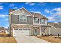 Charming two-story home featuring stone accents, neutral siding, an attached two-car garage, and a bright blue front door at 517 Southwick Pl, Mebane, NC 27302