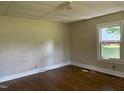 Bright bedroom featuring wood floors, neutral walls, and a window offering natural light and a view of the outdoors at 1200 Carolina St, Graham, NC 27253
