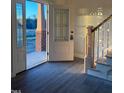 Sunlit foyer featuring wood-look floors, stairs with white railings, and a glass front door at 7575 Sweetwater Dr, Nashville, NC 27856