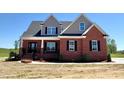 Charming two-story brick home with black shutters, a well maintained lawn, and a concrete sidewalk at 7575 Sweetwater Dr, Nashville, NC 27856