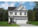 Exterior elevation of a white two-story home with a black roof, white garage door and a manicured lawn at 8816 Melvin St # 15, Willow Springs, NC 27592