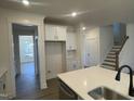 Bright kitchen featuring white cabinets, an island with a sink, and hardwood floors, with a view of stairs at 115 Arundel Dr, Archer Lodge, NC 27527
