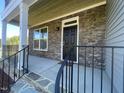 Inviting front porch with stone accents, black railing, covered ceiling and charming front door at 118 Arundel Dr, Archer Lodge, NC 27527