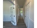 Hallway with gray wood floors, white trim, and a view of a bright room with deck access at 118 Arundel Dr, Archer Lodge, NC 27527