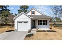 Charming white home featuring an attached garage, gray door, wooden pillars and shutters, and freshly installed sod at 5093 Nc 56 Hwy, Franklinton, NC 27525