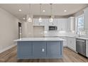 Modern kitchen featuring an island with a blue base, pendant lighting, stainless steel appliances, and white cabinets at 5093 Nc 56 Hwy, Franklinton, NC 27525
