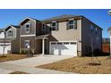 Two-story house with brown and beige siding, a white garage door, and a small yard at 332 Squirrel Oaks Ln, Garner, NC 27529