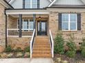 Inviting front porch with brick stairs, contrasting black door and black window shutters at 184 Dereham Ln, Garner, NC 27529