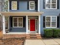 Inviting home exterior featuring a red door, black shutters, and a cozy porch swing at 5600 Thornburg Dr, Wake Forest, NC 27587