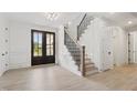 Inviting home entryway featuring hardwood floors, staircase with iron railing, and black-framed front door at 617 Darian Woods Dr, Holly Springs, NC 27540