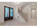 The bright foyer shows the front door and beautiful staircase with dark metal balusters at 617 Darian Woods Dr, Holly Springs, NC 27540