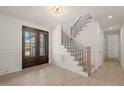 Inviting foyer with beautiful wood-look floors, dark-framed front doors, and an adjacent staircase at 617 Darian Woods Dr, Holly Springs, NC 27540