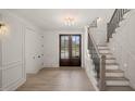 Light, bright foyer with beautiful floors, dark-framed front doors, and an adjacent staircase at 617 Darian Woods Dr, Holly Springs, NC 27540