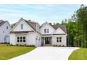Charming two-story home with a stone and white facade, manicured lawn, and long driveway at 617 Darian Woods Dr, Holly Springs, NC 27540