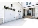 View of the two-car garage and covered front porch with stone steps leading to a wood door at 617 Darian Woods Dr, Holly Springs, NC 27540