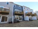 View of townhome backyards featuring sliding doors to balconies above and patios below at 2325 Bay Minette Sta # 548, Apex, NC 27502