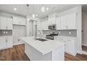 Modern kitchen featuring a center island, white cabinets, stainless steel appliances, and wood-look flooring at 622 Brittany Ct, Durham, NC 27703